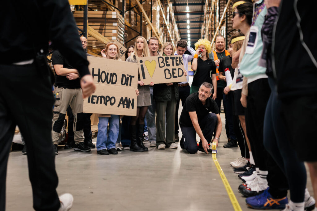 Medewerkers trekken een lijn voor een marathonwedstrijd terwijl supporters aanmoedigen in winkelomgeving